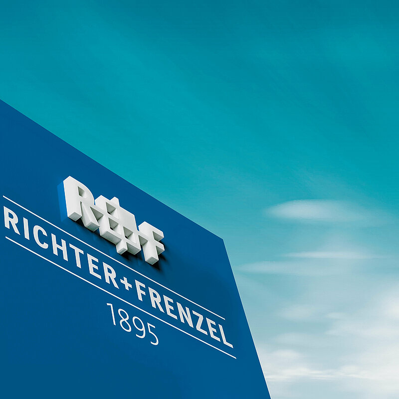 Dunkelblauer Pylon mit Aufschrift Richter+Frenzel vor blauem Himmel