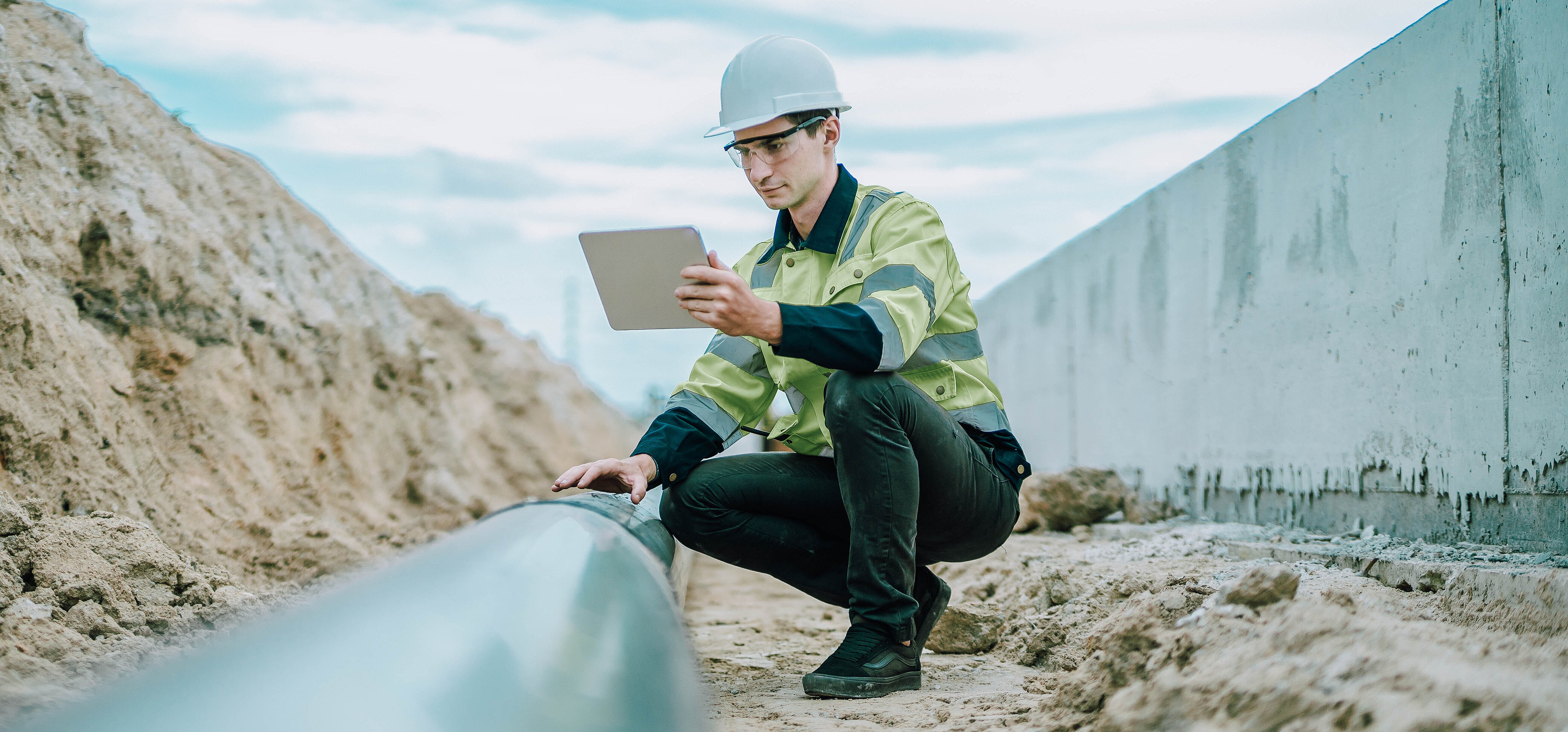 Arbeiter auf Baustelle in Hocke mit Tablet in der Hand