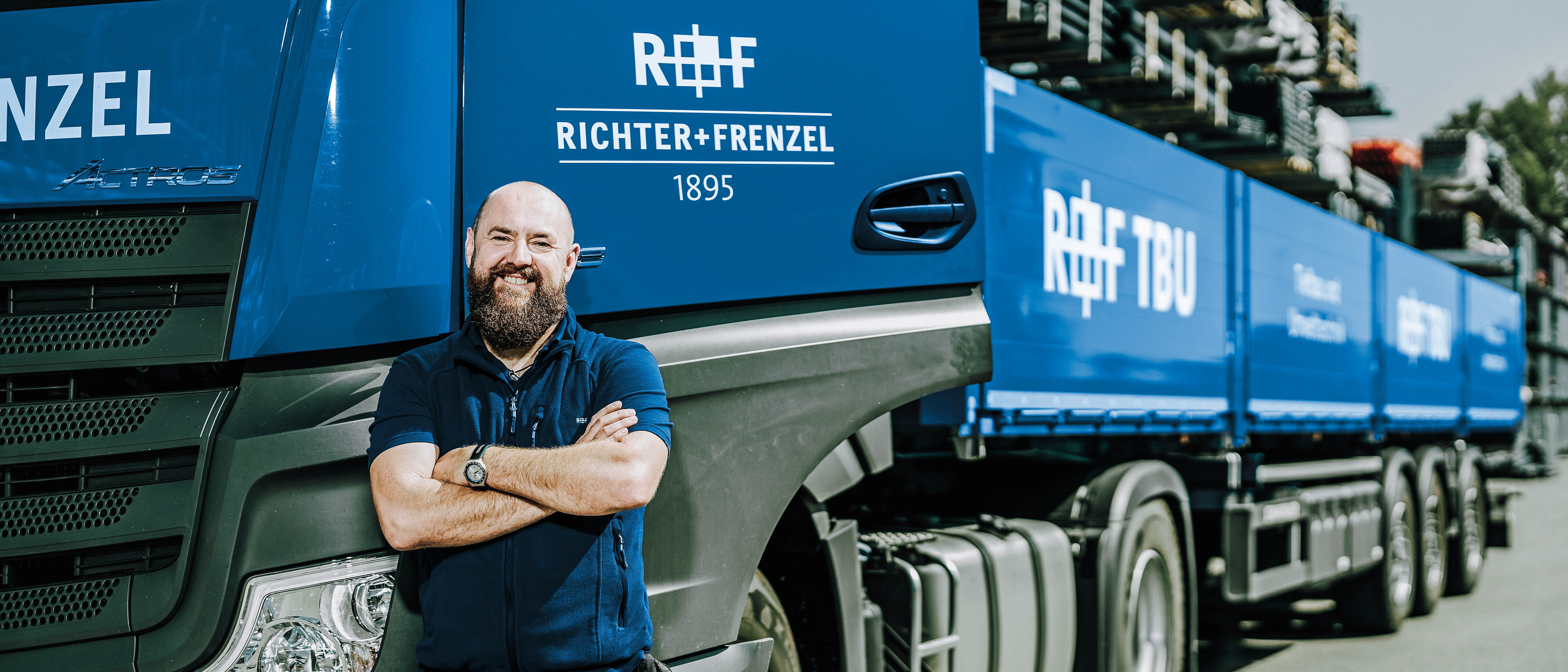 LKW-Fahrer mit verschränkten Armen vor dem Tiefbau-LKW