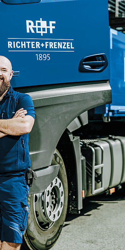 R+F TBU LKW-Fahrer LKW-Fahrer mit verschränkten Armen vor einem Tiefbau-LKW