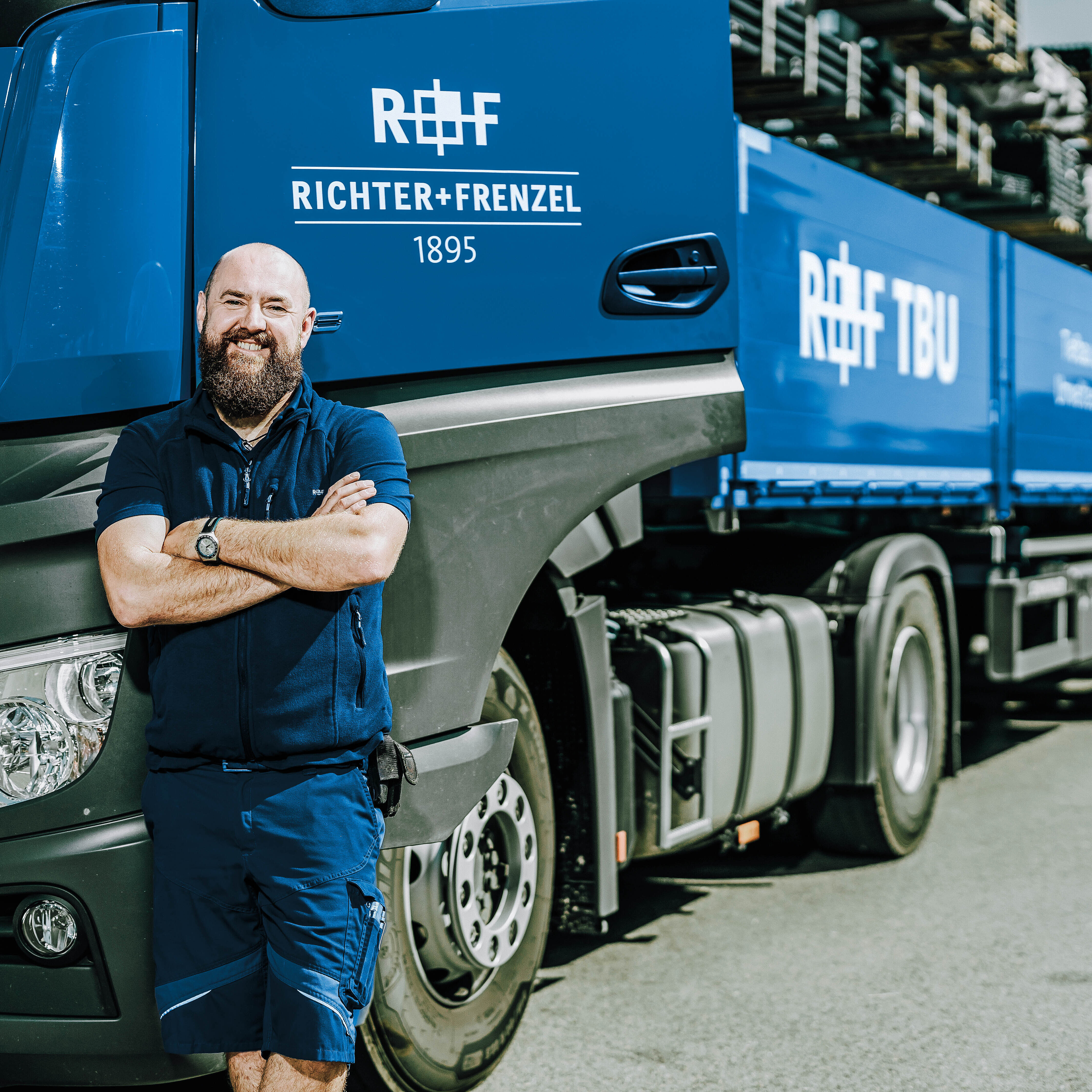 LKW-Fahrer mit verschränkten Armen vor dem Tiefbau-LKW